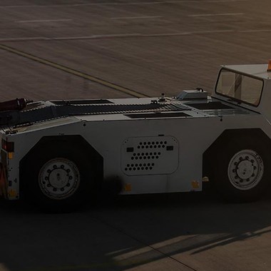 white airport vehicle with an empty trailer