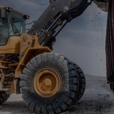 a yellow excavator tipping a load of soil into a container