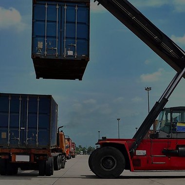 red vehicle with a crane arm handling a container