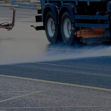 two red trucks cleaning a street with pressure washers