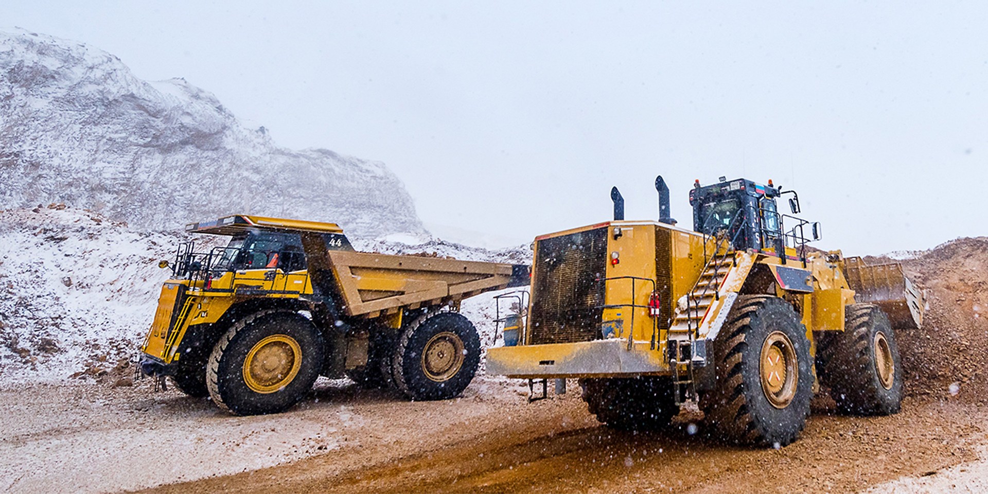 two excavators operating on a construction site in the mountains
